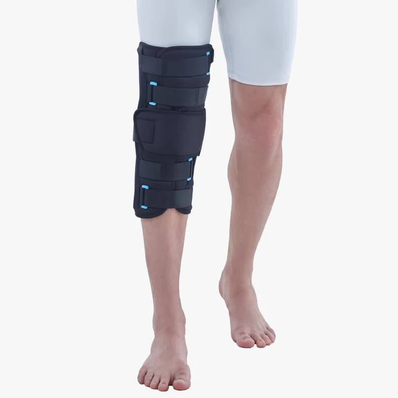 Man standing with the navy Vissco 14-inch knee immobiliser on one leg